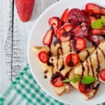 Strawberry crepe cookie topped with fresh strawberries and whipped cream
